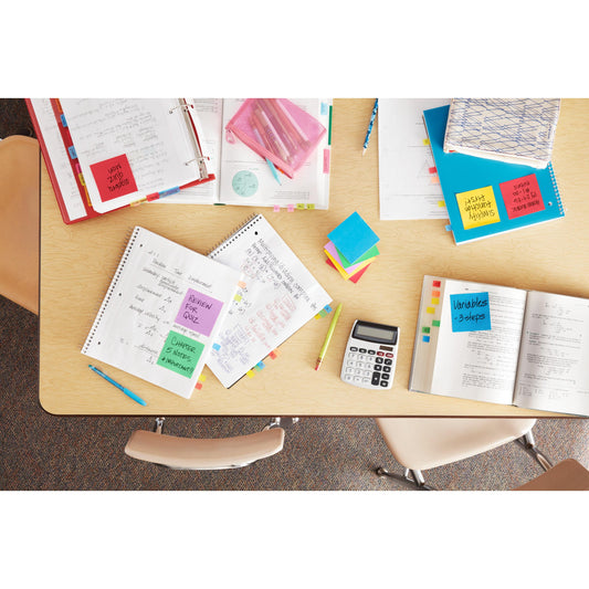 Ein Tisch mit offenen Notizbüchern, Stiften, Ordnern und einem Taschenrechner ist von oben zu sehen. Die Papiere sind mit 3M Post-it® Super Sticky Z-Notes Promotion (verschiedene Neonfarben, 76x127mm) zum schnellen Nachschlagen organisiert; drei leere Stühle umgeben den Tisch.