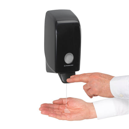 Κάποιος βάζει σαμπουάν μαλλιών και σώματος Kleenex® της Kimberly-Clark GmbH από μια λευκή επιτοίχια κασέτα 1 λίτρου στην παλάμη του και πατάει τον μοχλό για αποτελεσματικό καθαρισμό και απαλή φροντίδα.