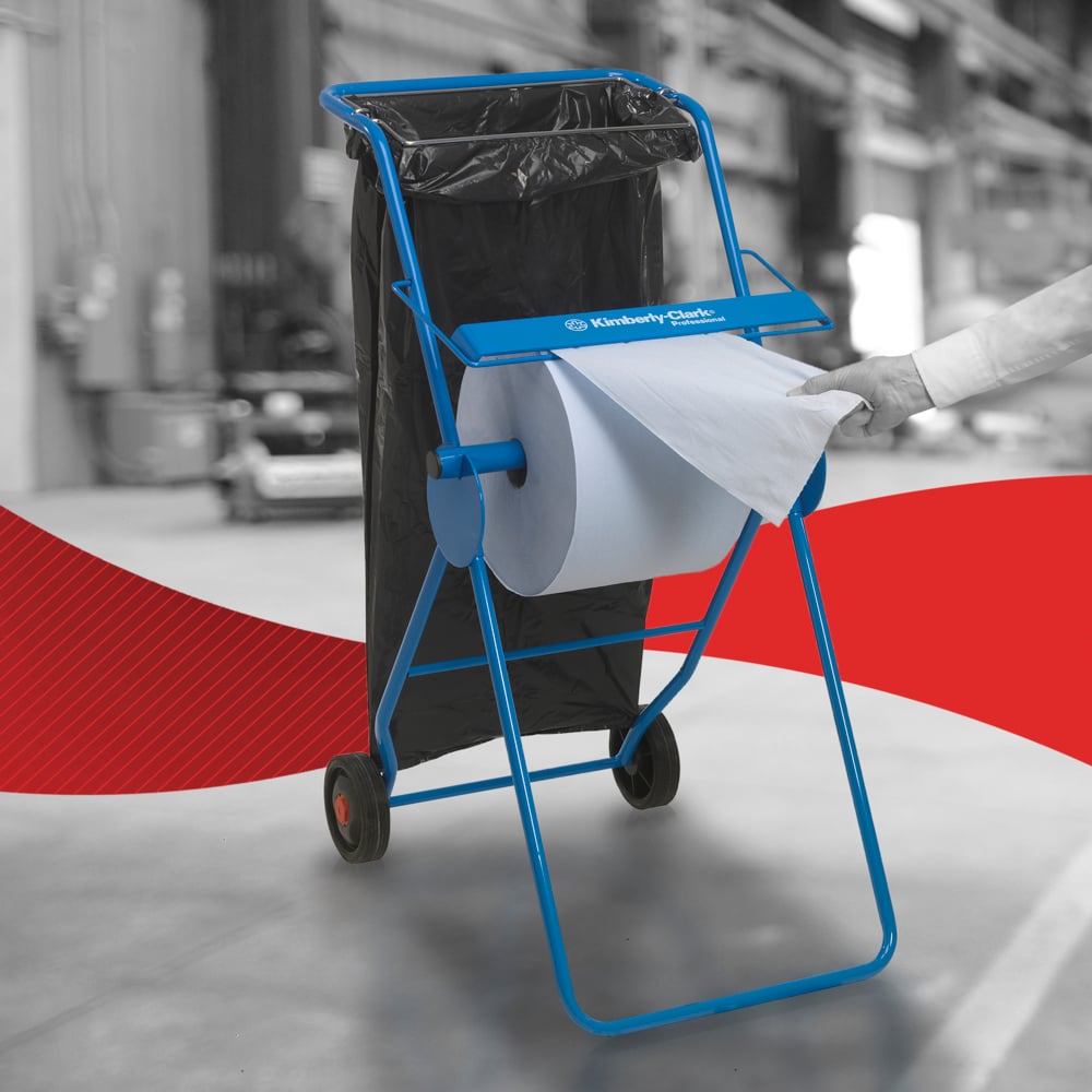 Eine Person zieht ein WypAll® L10 Papierwischtuch für Oberflächen - Großrolle (38,00 x 23,50 cm) der Kimberly-Clark GmbH von einem blauen Metallständer mit Rädern und einem daran befestigten schwarzen Müllsack, was auf eine effiziente Oberflächenreinigung in industriellen Umgebungen hindeutet.