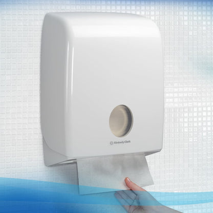 Ένα χέρι τραβάει μια Scott® Control™ Interfold Χαρτοπετσέτα από έναν λευκό διανομέα Kimberly-Clark σε ένα πλακάκι μπάνιο, εξασφαλίζοντας υγιεινό στέγνωμα χεριών.