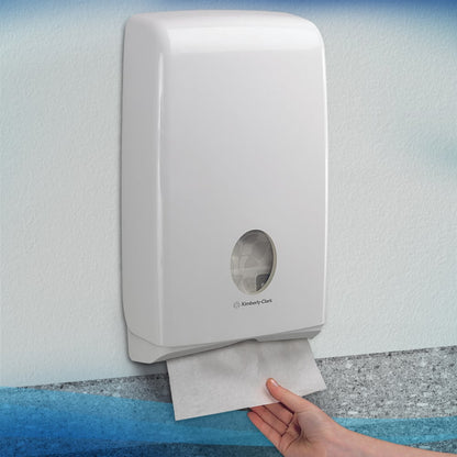 Ένα χέρι τραβάει μια Scott® SLIMFOLD χαρτοπετσέτα από έναν λευκό τοίχο διανομέα της Kimberly-Clark GmbH με παράθυρο προβολής, που δείχνει διπλωμένες χαρτοπετσέτες στο εσωτερικό. Ο υγιεινός διανομέας είναι τοποθετημένος σε έναν φωτεινό τοίχο. Χωράει 16 κλιπ x 110 φύλλα ανά κουτί.