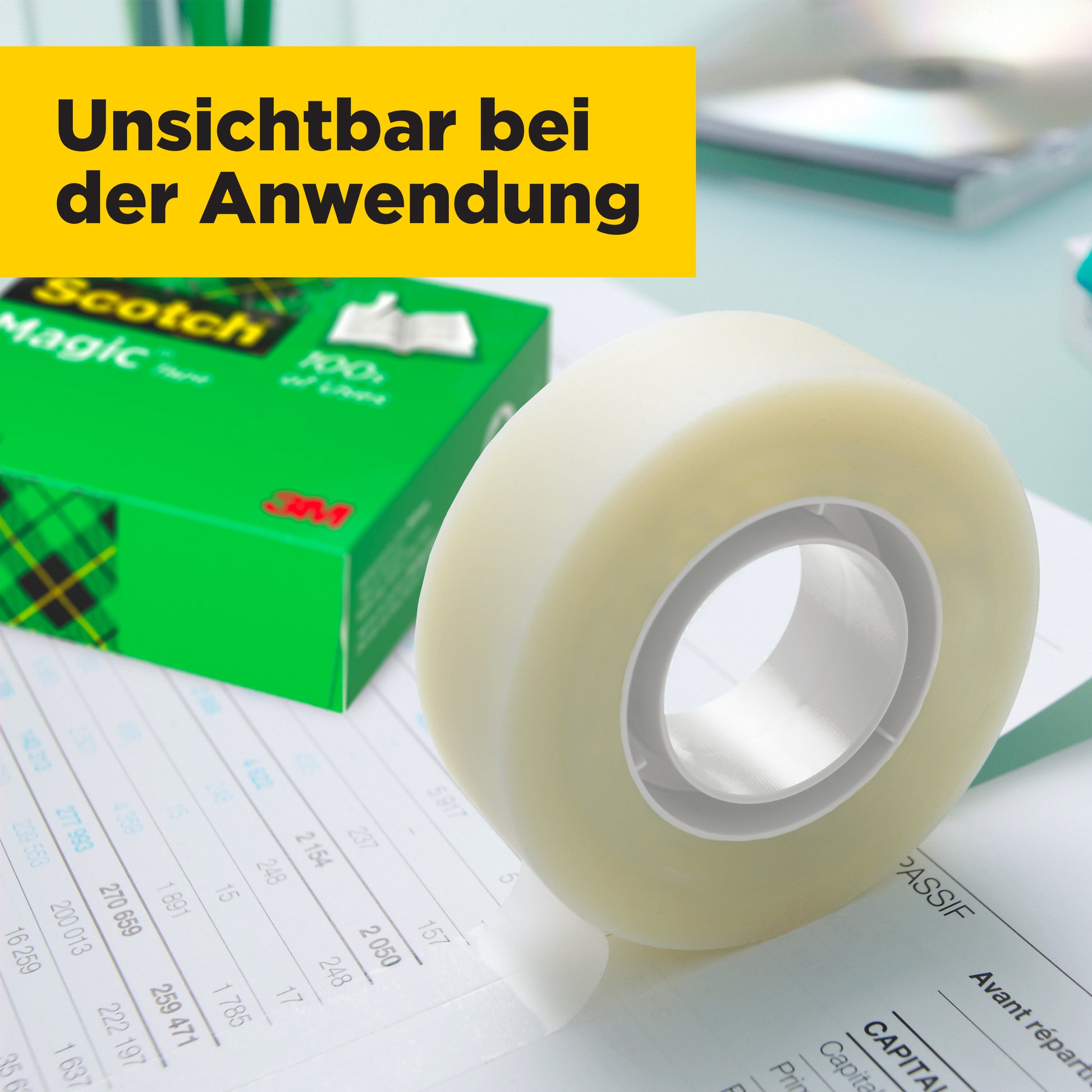 Eine Rolle Scotch® Magic™ Unsichtbares Klebeband von 3M Deutschland GmbH liegt auf einem Schreibtisch; im Hintergrund sind Dokumente und eine grüne Box. Ein gelbes Banner zeigt: "Unsichtbar bei der Anwendung." Vorteilspack mit 14 Rollen erhältlich.
