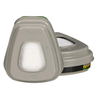 Απεικονίζονται δύο γκρι κασέτες συνδυαστικών φίλτρων 3M™ 6004-1 ABEK1P3 (2x6059, 2x5935, 2x501) από την 3M Deutschland GmbH - μία όρθια, μία πλάγια - με ορατές ετικέτες και σημάδια. Η συσκευασία περιέχει 1 τεμάχιο.