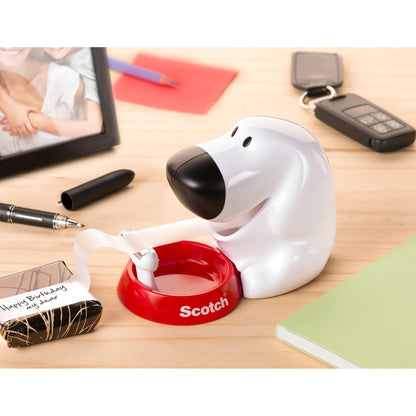 Der Scotch™ Tischabroller im Hunde Design C31 mit Scotch® Magic™ unsichtbarem Klebeband (19 mm x 8,89 m, 1 Rolle/Packung) von 3M Deutschland GmbH steht auf dem Schreibtisch zwischen Bürobedarf wie Notizbuch und Marker.