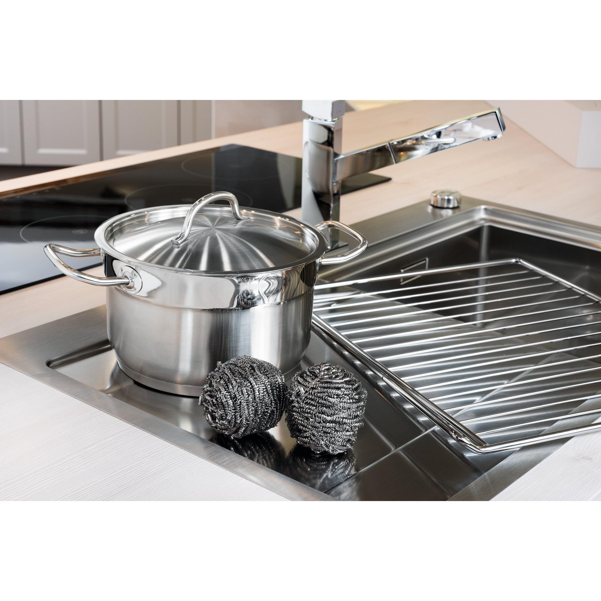 Ein Edelstahltopf mit Deckel steht in der Spüle neben zwei Scotch-Brite® Edelstahl-Spiralen (3M Deutschland GmbH, 3 Stück pro Packung) und einem Abtropfgestell - für einfache Küchenreinigung selbst bei hartnäckigen Verschmutzungen.