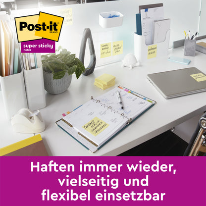Ein moderner Schreibtisch mit Laptop, Planer, Vorräten und Post-it® Super Sticky Notes im Großformat (101 mm x 101 mm, liniert, 45 Blatt/Block, 100% PEFC) von 3M Deutschland GmbH, die auf Oberflächen angebracht sind. Text: "Immer wieder haften, vielseitig und flexibel einsetzbar.
