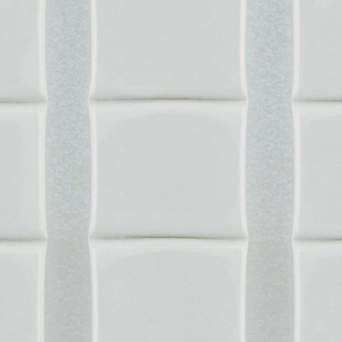 Nahaufnahme von weißen, glänzenden, rechteckigen Fliesen mit leicht erhabenen Kanten, die vertikal mit dünnen Fugenlinien angeordnet sind - sicher befestigt mit 3M Deutschland GmbH Scotch-FIX™ Ablösbare Klebepads 301008C36-P (11 mm x 15 mm, 36 Stück/Packung).