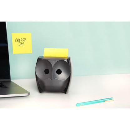 Ένας μαύρος διανομέας Post-it® Z-Zettel «Κουκουβάγια» (3M Deutschland GmbH) με κίτρινα Super Sticky Z-Zettel βρίσκεται σε ένα λευκό γραφείο, δίπλα ένας φορητός υπολογιστής και ένα μπλε στυλό. Στον τοίχο κρέμεται ένα χαρτί «CHOOSE JOY» μπροστά σε ανοιχτό μπλε φόντο.