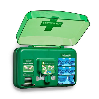 Ένας μπλε διανομέας φροντίδας τραυμάτων από την Orkla Wound Care AB είναι ανοιχτός και αποκαλύπτει πακέτα καθαρισμού τραυμάτων, επιθέματα και έναν ρόλο μαλακών αφρώδων επιδέσμων, που είναι τοποθετημένα σε ξεχωριστές θήκες.