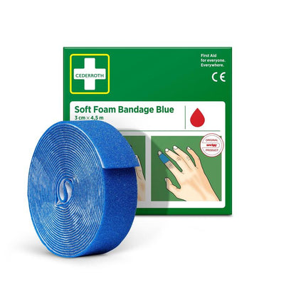 Eine Rolle Cederroth Soft Foam Binde blau 3x450cm von Orkla Wound Care AB ist vor der grün-weißen Verpackung abgebildet, auf der die blaue Binde um einen Finger gewickelt ist.