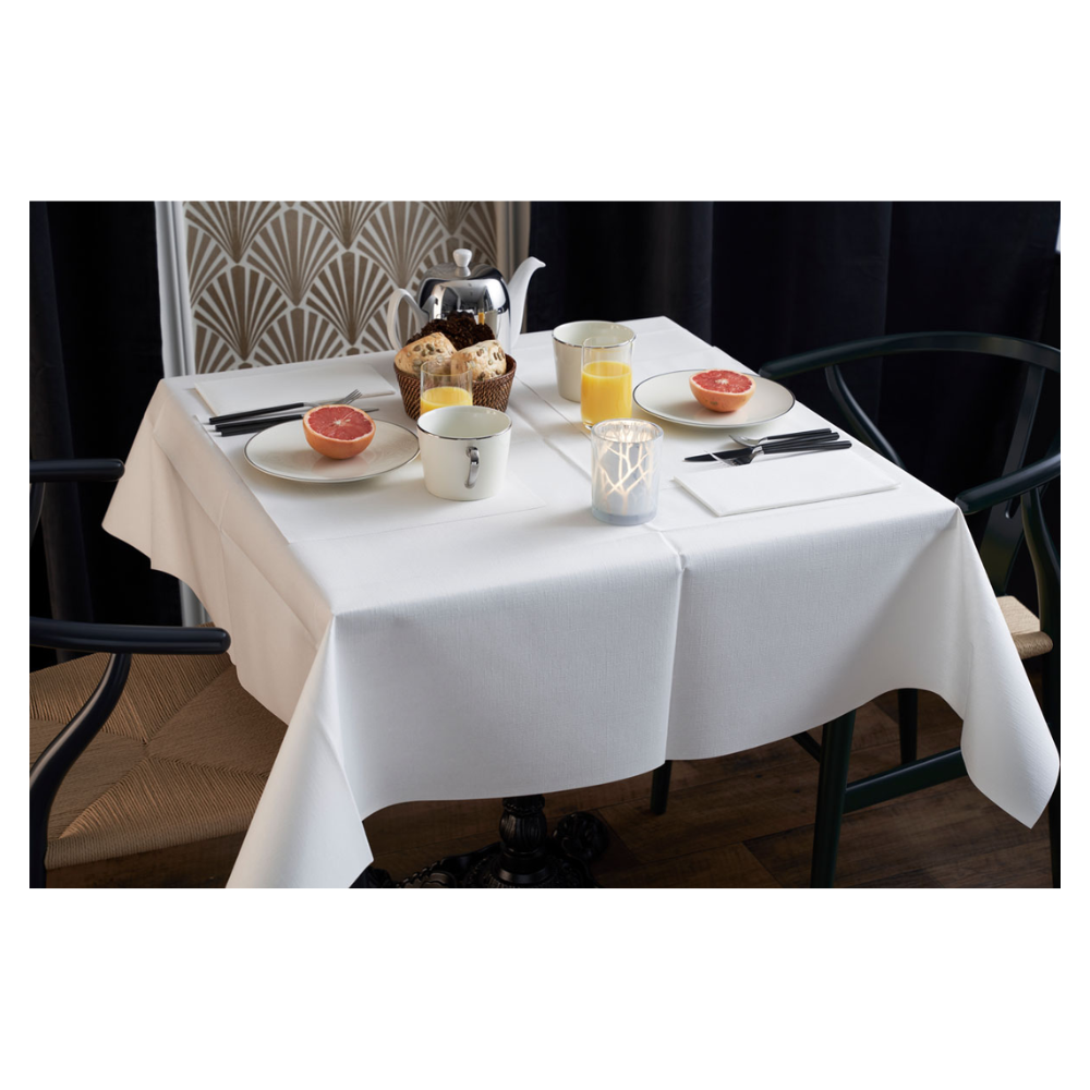 Το τραπέζι του πρωινού είναι κομψά στρωμένο με λευκό τραπεζομάντηλο, δύο καρέκλες και ένα βάζο με γεωμετρικό σχέδιο. Στο τραπέζι υπάρχουν μισά γκρέιπφρουτ, αρτοσκευάσματα, τσάι και χυμός πορτοκαλιού. Μια Duni Dunilin®-χαρτοπετσέτα (48x48 cm) της Duni GmbH προσδίδει γοητεία και λειτουργικότητα στο ατμοσφαιρικό πρωινό σερβίρισμα.