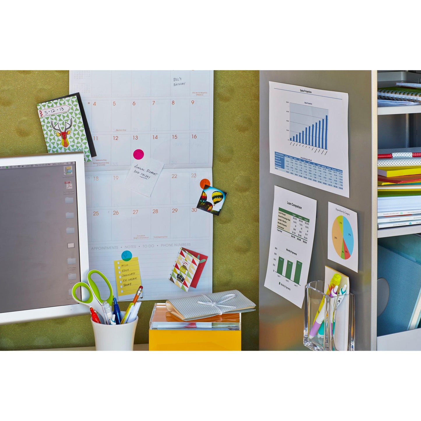 Ein Arbeitsplatz mit Kalender, Monitor und Büromaterial, an dem Tabellen und Diagramme mit 3M Deutschland GmbH Scotch-FIX™ Ablösbare Klebepads 301008C36-P (11 mm x 15 mm, 36 Stück/Packung) in der Nähe von Regalen mit Ordnern und Notizbüchern an die Wand geheftet werden.