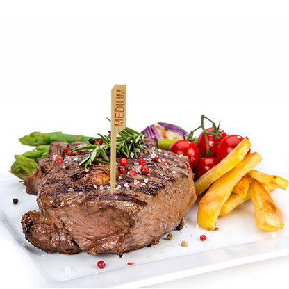 Ein gegrilltes Steak mit der Bezeichnung „medium“ und dem PAPSTAR 250 Steak-Marker 9 cm der PAPSTAR GmbH wird auf einem weißen Teller mit Pommes Frites, Spargel, Kirschtomaten, roten Zwiebeln und Kräutern serviert – perfekt für die professionelle Restaurantküche.