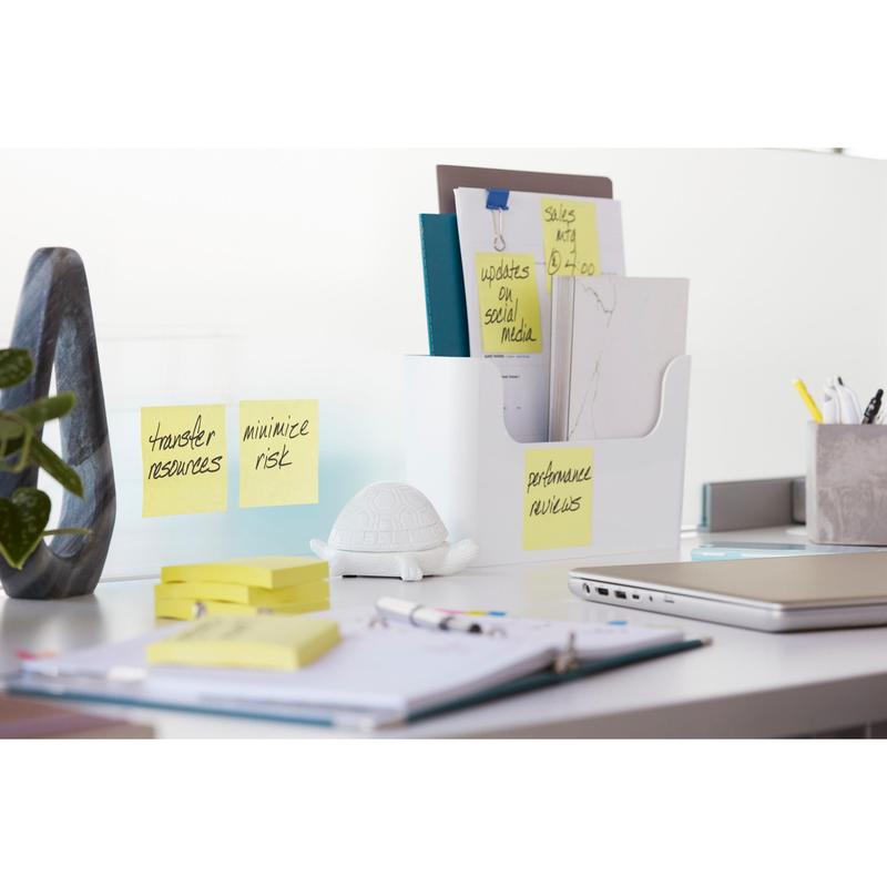 Ένα λευκό γραφείο με το Post-it® Z-Notes Dispenser PRO της 3M Deutschland GmbH σε μαύρο χρώμα με κίτρινες Post-it® Super Sticky Z-Notes (76x76 mm), μαζί με φακέλους, γραφική ύλη, ένα σημειωματάριο, ένα φορητό υπολογιστή, μια φιγούρα χελώνας και αυτοκόλλητες σημειώσεις στον τοίχο, στις οποίες αναγράφονται εργασίες.