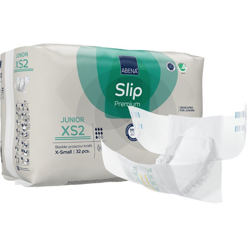 Μια συσκευασία ABENA Slip Junior Premium Gr XS2 από την Abena Re-Seller GmbH (32 τεμάχια) εκτίθεται με ένα προϊόν ακράτειας παιδικό slip δίπλα στη πράσινο-λευκή συσκευασία.