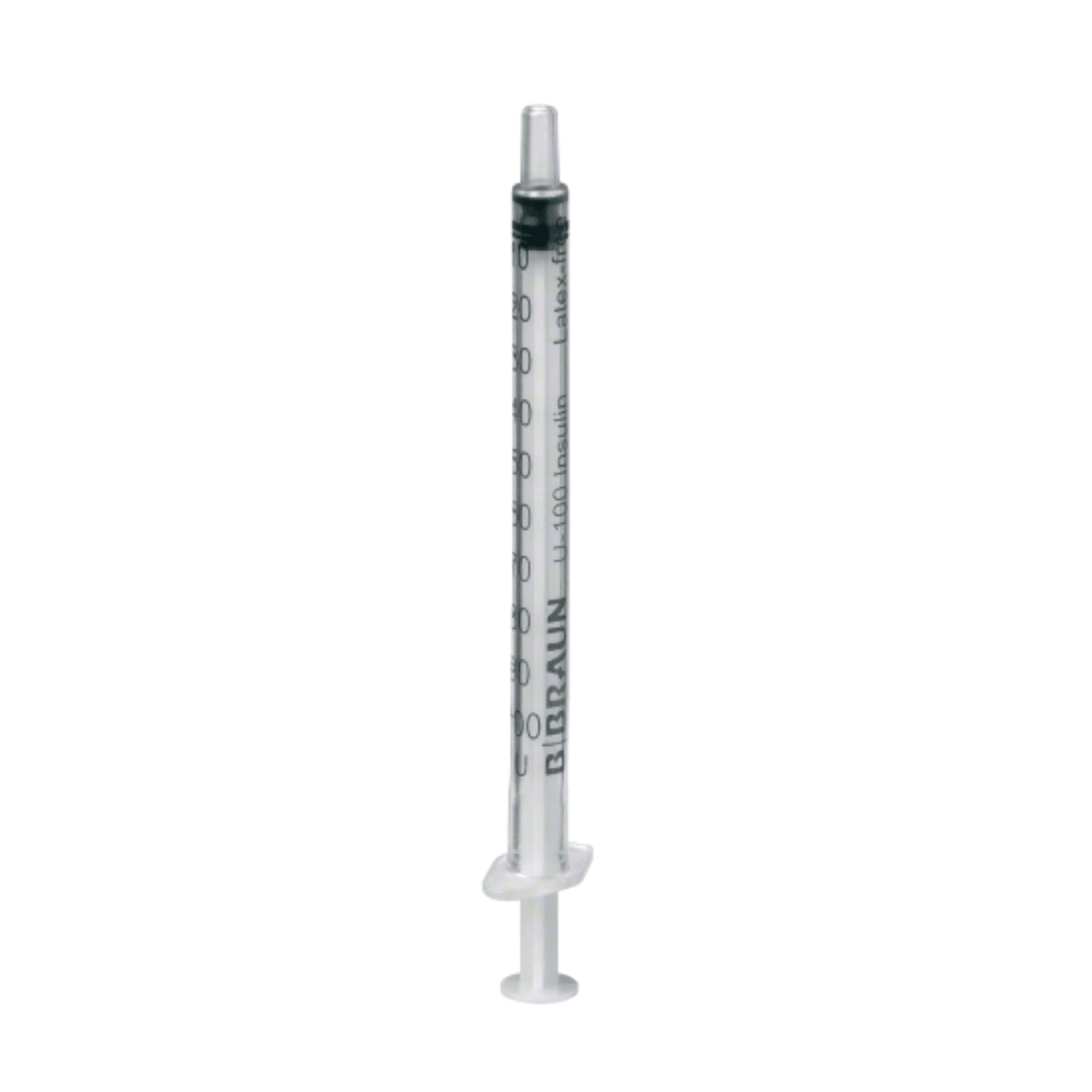 Μία διαφανής σύριγγα μιας χρήσης B.Braun Omnifix® 100 Solo για ινσουλίνη U-100, σχεδιασμένη για υποδόρια ένεση ινσουλίνης, με μαύρο καπάκι εμβόλου και γραμμές μέτρησης στο πλάι καθώς και την επιγραφή "BBRAUN", στέκεται όρθια μπροστά από ένα απλό λευκό φόντο.