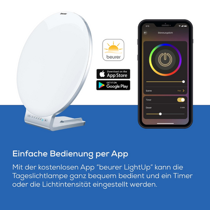 Die Beurer Tageslichtlampe TL 100 (Auslaufartikel) der Beurer GmbH ist in Weiß mit 10.000 Lux neben einem Smartphone mit der LightUp-App abgebildet, die per App-Store-Logos mit iOS und Android kompatibel ist; deutscher Text hebt die App-basierte Steuerung hervor.