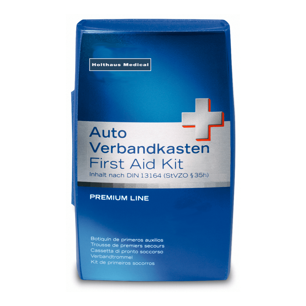 Ένα μπλε-λευκό κουτί με την επιγραφή «Holthaus Premium Erste-Hilfe-Set | Packung (1 Stück)» υποδεικνύει την ανθεκτικότητα στη θερμοκρασία και την αντοχή του στη θραύση. Ένα επιπλέον πολυγλωσσικό κείμενο ενημερώνει για το περιεχόμενο και τη συμμόρφωση με το DIN 13164 (StVZO §35h). Στην πάνω αριστερή γωνία αναγράφεται το όνομα της μάρκας «Holthaus Medical GmbH & Co. KG».