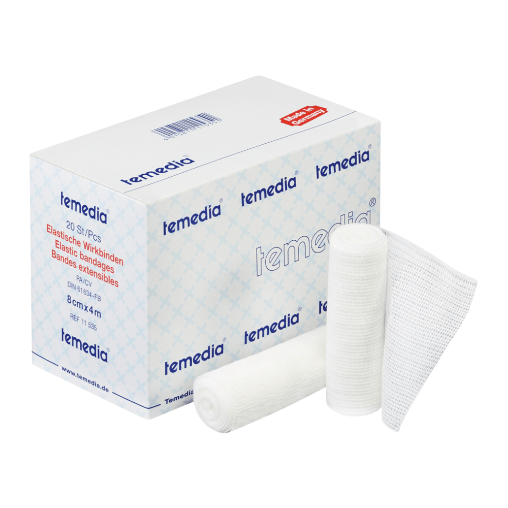 Ένα κουτί Holthaus Temedia® Wirkbinde, 10 cm x 4 m | Συσκευασία (20 τεμάχια) από την Holthaus Medical GmbH & Co. KG εκτίθεται, με το όνομα του προϊόντος και τις λεπτομέρειες στη συσκευασία ορατές. Δίπλα βρίσκονται δύο τυλιγμένοι ελαστικοί επίδεσμοι και ένα ξεδιπλωμένο κομμάτι γάζας. Η συσκευασία είναι σχεδιασμένη σε μπλε-λευκό, με κόκκινο κείμενο που αναφέρει τις ιατρικές προδιαγραφές του προϊόντος.