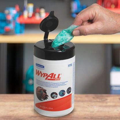 Ένα χέρι τραβάει ένα πράσινο WypAll® μαντηλάκι με υψηλή απορροφητικότητα από έναν ανοιχτό κάδο της Kimberly-Clark GmbH (6 κάδοι x 50 φύλλα). Στο θολό υπόβαθρο φαίνονται ράφια με διάφορα αντικείμενα.