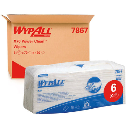 Μια συσκευασία WypAll® X70 μαντηλάκια - διπλωμένα / Λευκό (6 σακούλες x 70 μαντηλάκια) της Kimberly-Clark GmbH απεικονίζεται μπροστά από ένα κουτί με την επιγραφή "WypAll 7867". Η κόκκινη ετικέτα "6x" αναδεικνύει τα μαντηλάκια καθαρισμού βιομηχανικής ποιότητας με μπλε επωνυμία.