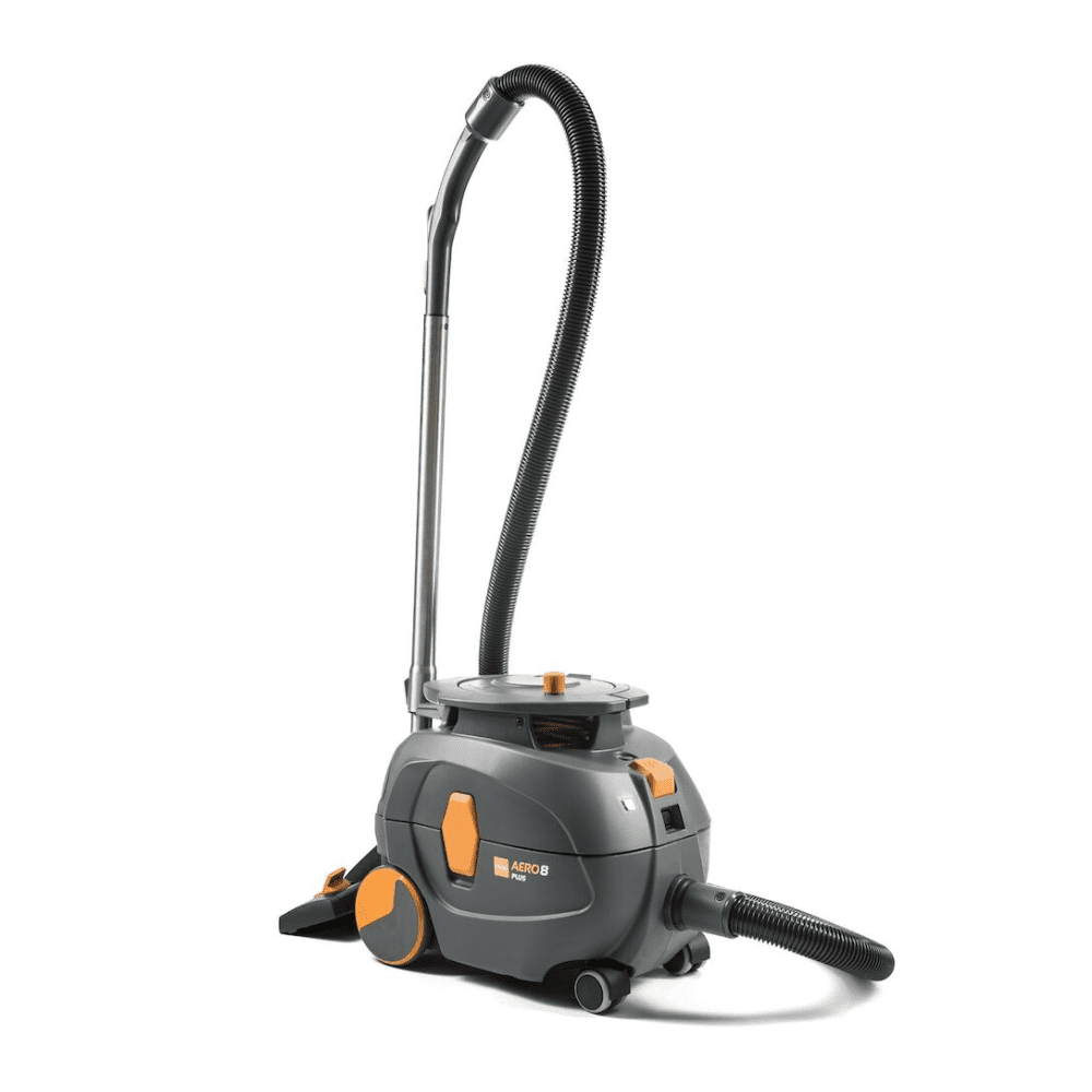 Μια ηλεκτρική σκούπα TASKI AERO 8 PLUS, που παρέχεται από την Diversey Deutschland GmbH & Co. OHG, σε γκρι και πορτοκαλί, στέκεται όρθια. Αυτή η συμπαγής και ισχυρή σκούπα διαθέτει έναν μακρύ ευέλικτο σωλήνα και έχει κυλινδρικό σώμα με μεγάλους πίσω τροχούς και μικρότερους μπροστινούς τροχούς για εξαιρετική κινητικότητα και αποτελεσματικό καθάρισμα. Η λειτουργία της βελτιώνεται από την τεχνολογία ψιθυρίσματος για αθόρυβη λειτουργία.