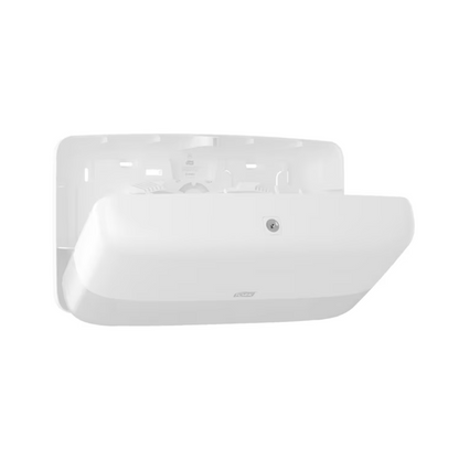 Μια λευκή, ορθογώνια μονάδα τοίχου από τη σειρά TORK - Essity Professional Hygiene Germany GmbH με λείο, καμπύλο σχέδιο. Στην μπροστινή πλευρά φαίνεται ένα λογότυπο και υπάρχει ένας αισθητήρας για εύκολη ενεργοποίηση. Το μοντέλο διαθέτει έναν εσοχή για αποδοτική χρήση.