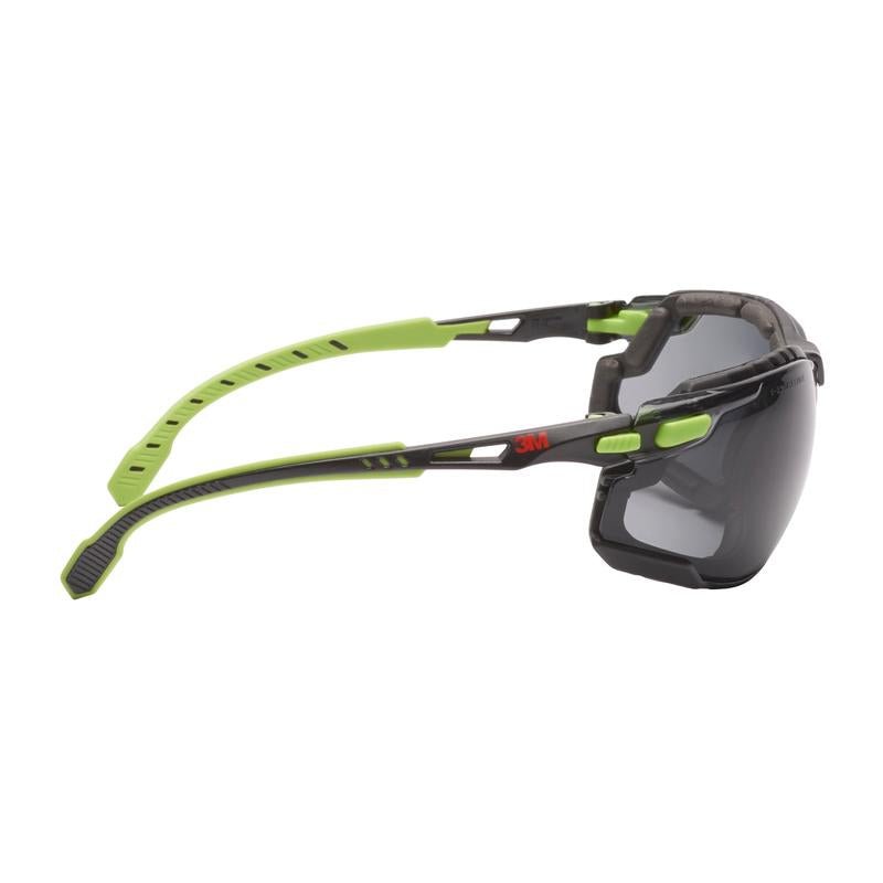 Ένα γυαλί προστασίας 3M™ Solus™ 1000 από την 3M Deutschland GmbH σε πράσινο/μαύρο με επίστρωση κατά της ομίχλης Scotchgard™, αποσπώμενη σφράγιση αφρού και γκρι γυαλιά σε πλάγια όψη σε λευκό φόντο.
