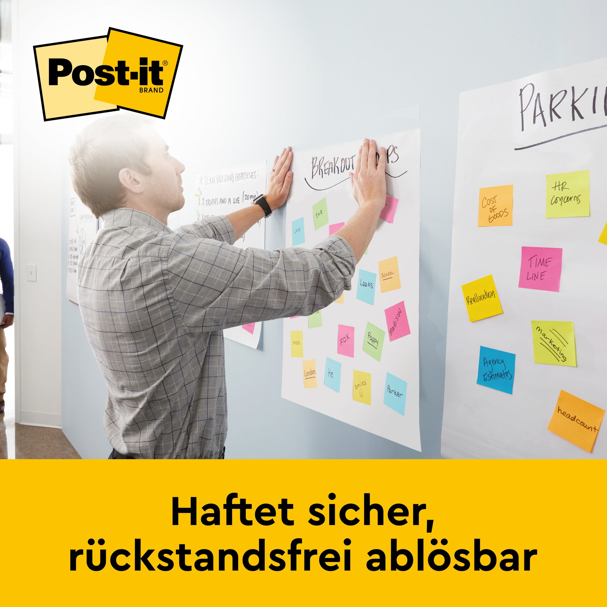 Ein Mann klebt bunte Post-it® Super Sticky Meeting Chart Blätter von 3M Deutschland GmbH (58,4 x 50,8 cm, 20 Blatt/Block) an eine Bürowand. Darunter steht: "Haftet sicher, rückstandsfrei ablösbar.