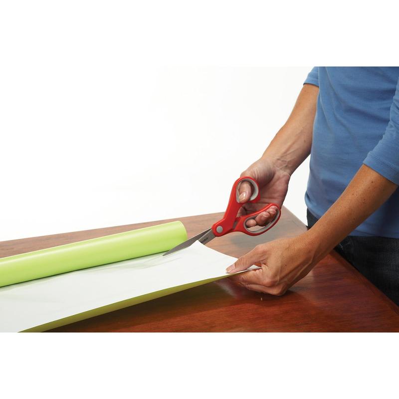 Ένα άτομο με μπλε πουκάμισο χρησιμοποιεί το κόκκινο ψαλίδι ακρίβειας Scotch™ από την 3M Deutschland GmbH για να κόψει μερικώς ξετυλιγμένο ανοιχτό πράσινο χαρτί ή βινύλιο σε ξύλινη επιφάνεια.