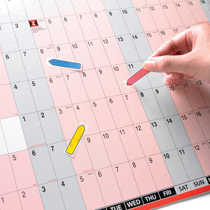 Eine Hand platziert einen roten Post-it® Index Pfeil (11,9 mm x 43,2 mm) der 3M Deutschland GmbH auf einem Kalender, blaue und gelbe Pfeile markieren weitere Termine auf dem schwarz-gedruckten, rosa und grauen Hintergrund. Jeder Spender enthält 100 Haftstreifen.