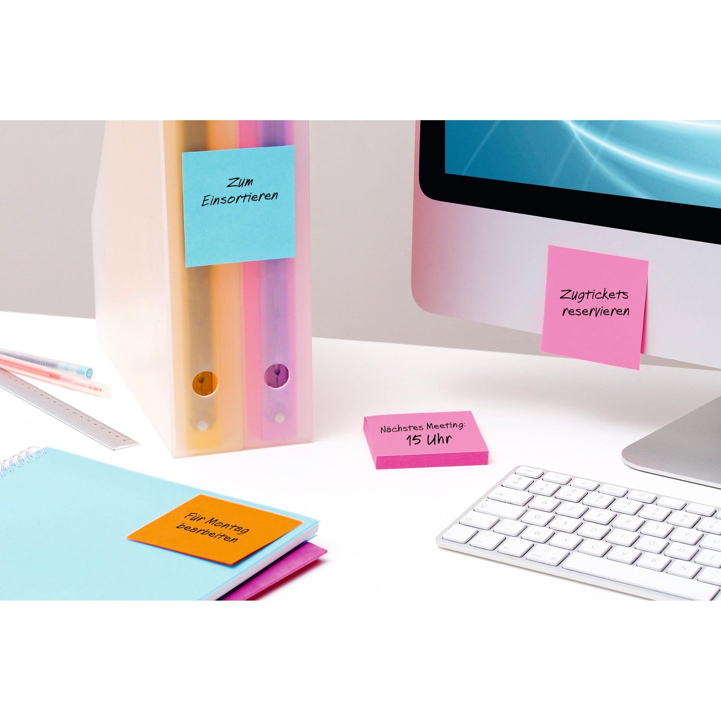 Auf dem Schreibtisch liegen ein Computer, eine Tastatur, Ordner, Lineal, Notizbuch und bunte Post-it® Super Sticky Notes Würfel (76 x 76 mm, 100% PEFC) von 3M Deutschland GmbH für Meeting-Erinnerungen und Organisation.