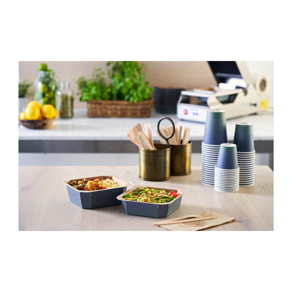 Στο τραπέζι βρίσκονται δύο μπολ για φαγητό, πλαισιωμένα από στοιβαγμένα Duni Urban Kaffeebecher PAP/PLA της Duni GmbH, ξύλινα μαχαιροπίρουνα σε μια θήκη και χαρτοπετσέτες. Λεμόνια, ποτήρια και βότανα στο παρασκήνιο συμβάλλουν στη βιώσιμη ατμόσφαιρα αυτού του χώρου προετοιμασίας φαγητού.